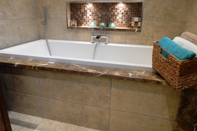 Drop-in bathtub - mid-sized traditional kids' beige tile and porcelain tile marble floor and beige floor drop-in bathtub idea in London with furniture-like cabinets, medium tone wood cabinets, a wall-mount toilet, beige walls and marble countertops