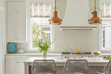Transitional l-shaped medium tone wood floor and brown floor open concept kitchen photo in Charleston with a farmhouse sink, white cabinets, quartz countertops, gray backsplash, porcelain backsplash, paneled appliances, an island and white countertops