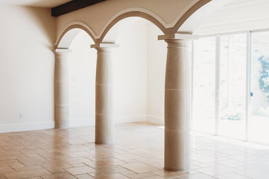 Example of a mid-sized tuscan enclosed travertine floor and brown floor living room design in New Orleans with white walls