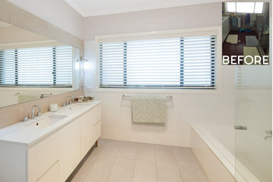 This is an example of a large contemporary master bathroom in Sydney with white cabinets, a drop-in tub, a corner shower, a one-piece toilet, beige tile, porcelain tile, beige walls, ceramic floors, an undermount sink, engineered quartz benchtops, beige floor, a hinged shower door, white benchtops, a double vanity and a freestanding vanity.