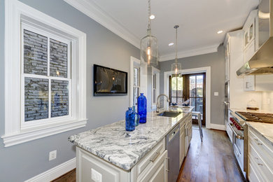 Inspiration for a small transitional galley medium tone wood floor and brown floor eat-in kitchen remodel in DC Metro with an undermount sink, raised-panel cabinets, white cabinets, granite countertops, white backsplash, glass tile backsplash, stainless steel appliances and an island
