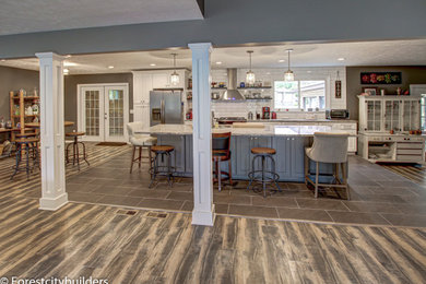 Example of a large minimalist single-wall laminate floor eat-in kitchen design in Cleveland with an undermount sink, shaker cabinets, white cabinets, granite countertops, white backsplash, ceramic backsplash, stainless steel appliances and an island