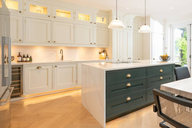 Photo of a large classic open plan kitchen in Hertfordshire with a single-bowl sink, shaker cabinets, white cabinets, white splashback, stainless steel appliances, an island and white worktops.