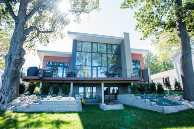 Example of a large trendy brown two-story concrete house exterior design in Grand Rapids with a shed roof and a metal roof