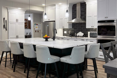 Large transitional single-wall vinyl floor and beige floor eat-in kitchen photo in Other with a farmhouse sink, shaker cabinets, white cabinets, quartz countertops, black backsplash, subway tile backsplash, stainless steel appliances, an island and white countertops