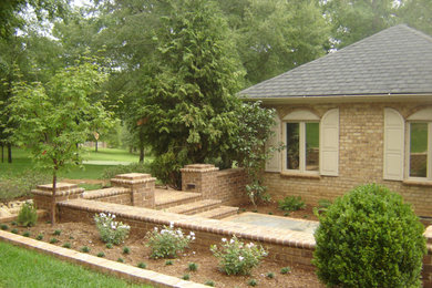 Large traditional side yard full sun garden in Other with a retaining wall and brick pavers.