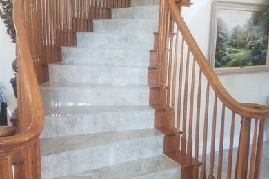 Diseño de escalera curva tradicional de tamaño medio con escalones con baldosas, contrahuellas con baldosas y/o azulejos y barandilla de madera