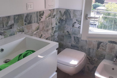 Foto di un piccolo bagno di servizio moderno con WC sospeso, piastrelle multicolore, piastrelle in gres porcellanato, pareti multicolore, pavimento in laminato e lavabo integrato