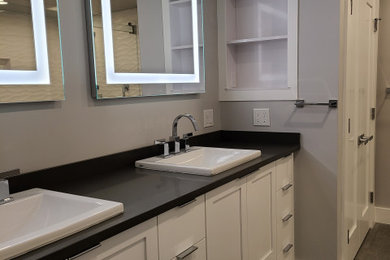 Example of a huge minimalist master white tile and porcelain tile porcelain tile, gray floor and double-sink bathroom design in Boston with shaker cabinets, white cabinets, a two-piece toilet, gray walls, a drop-in sink, quartz countertops, black countertops and a built-in vanity
