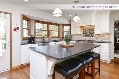 Example of a mid-sized transitional l-shaped medium tone wood floor kitchen design in Philadelphia with an undermount sink, shaker cabinets, white cabinets, granite countertops, gray backsplash, subway tile backsplash, stainless steel appliances and an island