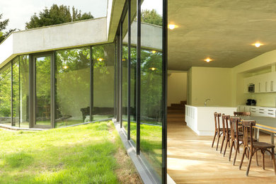 Réalisation d'une grande salle à manger ouverte sur la cuisine design avec un mur blanc, parquet clair et un sol beige.