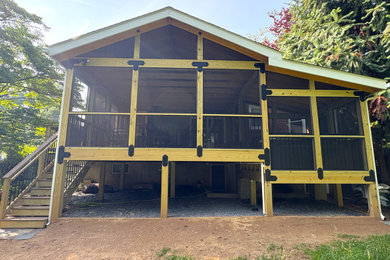 This is an example of a mid-sized craftsman screened-in and metal railing back porch design in DC Metro with decking and a roof extension.