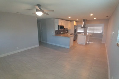 Foto de salón abierto actual de tamaño medio sin chimenea y televisor con paredes grises, suelo de baldosas de cerámica y suelo gris