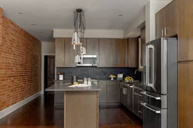 Example of a mid-sized urban l-shaped dark wood floor and brown floor kitchen design in DC Metro with a single-bowl sink, recessed-panel cabinets, brown cabinets, quartz countertops, black backsplash, ceramic backsplash, stainless steel appliances, an island and gray countertops