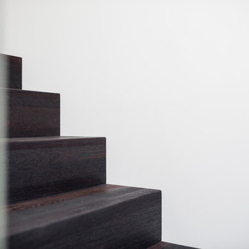 Faltwerk aus Wenge mit Weißglas auf Beton