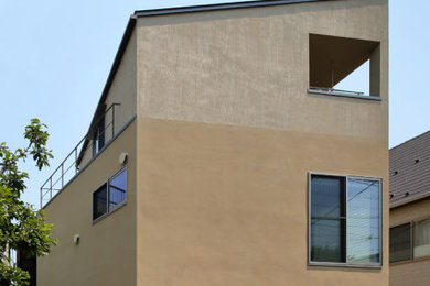 Example of a small beige three-story stucco house exterior design in Tokyo with a shed roof, a metal roof and a gray roof
