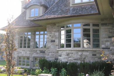 Large traditional two-storey grey exterior in Toronto with stone veneer.