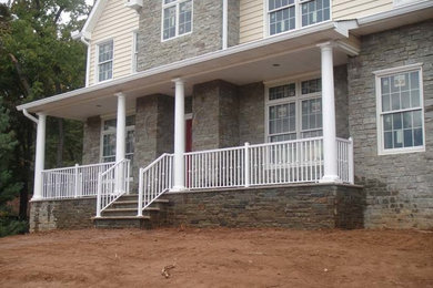 Mid-sized concrete paver front porch photo in New York with a roof extension