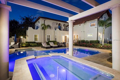 Photo of a large mediterranean backyard rectangular lap pool in Orlando with a pool house and concrete pavers.