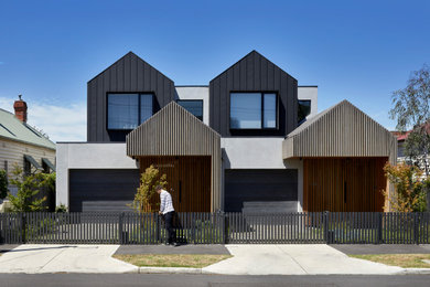 Modelo de fachada de casa bifamiliar negra actual de tamaño medio de dos plantas con revestimiento de madera, tejado a dos aguas y tejado de metal