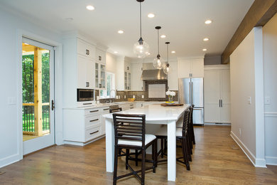 Inspiration for a large country l-shaped open plan kitchen in Raleigh with a single-bowl sink, shaker cabinets, white cabinets, quartz benchtops, grey splashback, ceramic splashback, stainless steel appliances, medium hardwood floors, with island, brown floor and white benchtop.