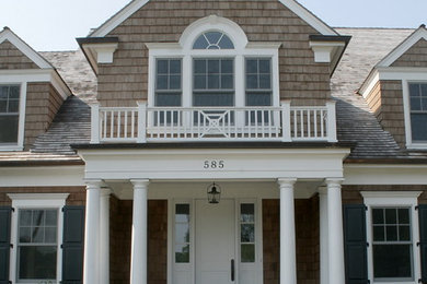This is an example of a large traditional two-storey brown house exterior in Chicago with wood siding, a gable roof and a shingle roof.