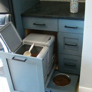 デンバーの大きいトランジショナルスタイルのおしゃれな家事室 (シェーカースタイル扉のキャビネット、青いキャビネット、御影石カウンター、白い壁、トラバーチンの床、上下配置の洗濯機・乾燥機、マルチカラーの床、黒いキッチンカウンター) の写真