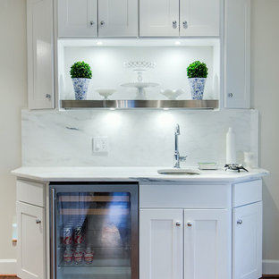 Medium sized modern single-wall wet bar in New York with a submerged sink, recessed-panel cabinets, white cabinets, marble worktops, grey splashback, stone slab splashback, medium hardwood flooring and white worktops.