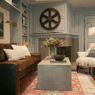 Foto på ett mellanstort maritimt hemmabibliotek, med blå väggar, mörkt trägolv, en öppen hörnspis, en spiselkrans i tegelsten och ett fristående skrivbord