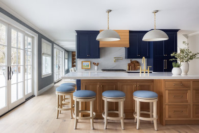 Inspiration for a large transitional l-shaped light wood floor enclosed kitchen remodel in New York with an undermount sink, quartz countertops, white backsplash, stone slab backsplash, an island and white countertops