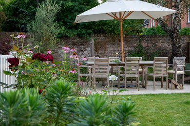 Design ideas for a medium sized traditional back patio in London with natural stone paving.