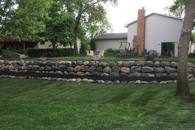 This is an example of a mid-sized rustic backyard retaining wall landscape in Minneapolis.