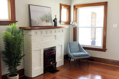 Inspiration for a small modern open concept medium tone wood floor and brown floor living room remodel in Toronto with gray walls, a standard fireplace, a brick fireplace and no tv