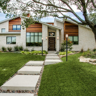 ダラスのミッドセンチュリースタイルのおしゃれな家の外観 (石材サイディング、ベージュの外壁、片流れ屋根、戸建) の写真