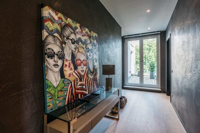 This is an example of a small contemporary hallway in Hamburg with black walls, light hardwood floors and beige floor.