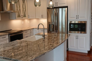 Example of a mid-sized beach style l-shaped medium tone wood floor and brown floor open concept kitchen design in Baltimore with a farmhouse sink, raised-panel cabinets, white cabinets, granite countertops, stainless steel appliances, an island and multicolored countertops