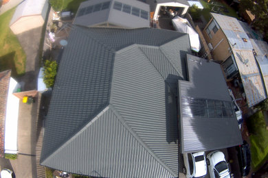 Photo of a mid-sized modern one-storey brick grey house exterior in Melbourne with a hip roof, a tile roof and a grey roof.