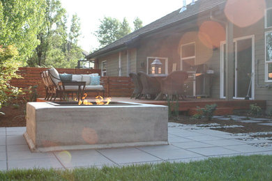 Design ideas for a mid-sized modern partial sun backyard concrete paver landscaping in Other with a fire pit.