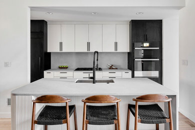 Large trendy u-shaped eat-in kitchen photo in Chicago with an undermount sink, flat-panel cabinets, white cabinets, quartzite countertops, white backsplash, porcelain backsplash, black appliances, an island and white countertops