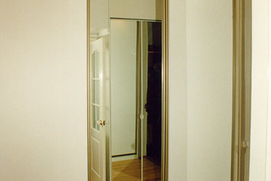 Стильный дизайн: узкая прихожая среднего размера в современном стиле с белыми стенами, светлым паркетным полом, раздвижной входной дверью, белой входной дверью и коричневым полом - последний тренд