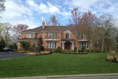 Large traditional two-story brick exterior home idea in New York