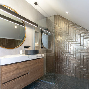 Mid-sized contemporary 3/4 bathroom in Central Coast with laminate benchtops, flat-panel cabinets, dark wood cabinets, an alcove shower, brown tile, grey walls, a vessel sink, black floor and an open shower.
