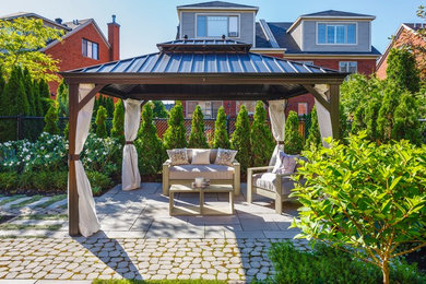 This is an example of a mid-sized transitional backyard patio in New York with concrete pavers and a gazebo/cabana.