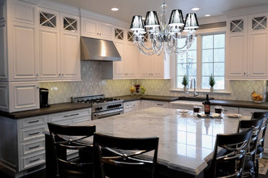 Mid-sized transitional l-shaped dark wood floor open concept kitchen photo in Newark with a farmhouse sink, raised-panel cabinets, quartzite countertops, gray backsplash, marble backsplash, paneled appliances, an island and white cabinets