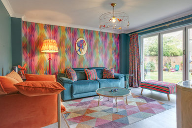 Design ideas for a medium sized contemporary enclosed living room feature wall in Essex with blue walls, laminate floors, a wall mounted tv and wallpapered walls.