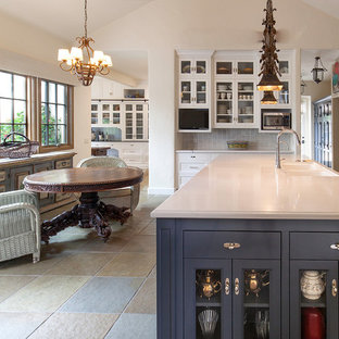 Свежая идея для дизайна: огромная кухня в классическом стиле с кладовкой, раковиной в стиле кантри, фасадами с утопленной филенкой, белыми фасадами, столешницей из кварцевого композита, фартуком из дерева, полом из сланца, островом, зеленым полом и черной столешницей - отличное фото интерьера