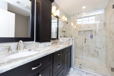 Photo of a mid-sized traditional 3/4 bathroom in DC Metro with recessed-panel cabinets, black cabinets, an alcove shower, beige tile, gray tile, marble, grey walls, marble floors, an undermount sink, granite benchtops, grey floor and a hinged shower door.
