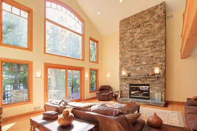 Example of a large transitional formal and open concept medium tone wood floor living room design in Other with yellow walls, a standard fireplace, a stone fireplace and no tv