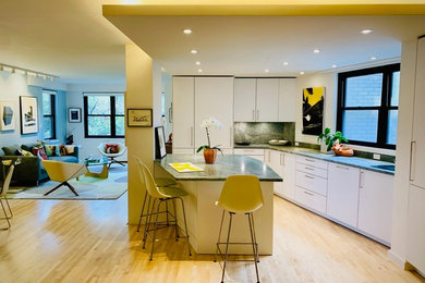 Example of a mid-sized minimalist l-shaped light wood floor and beige floor open concept kitchen design in New York with an undermount sink, flat-panel cabinets, white cabinets, soapstone countertops, multicolored backsplash, stone slab backsplash, stainless steel appliances, an island and multicolored countertops