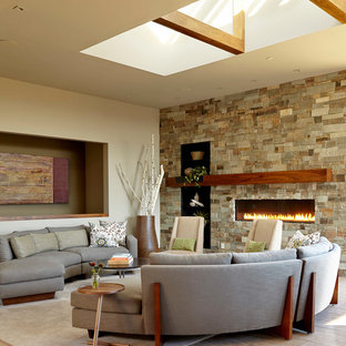 Idéer för ett stort modernt allrum med öppen planlösning, med en bred öppen spis, en spiselkrans i sten, beige väggar, ljust trägolv, en väggmonterad TV och grått golv